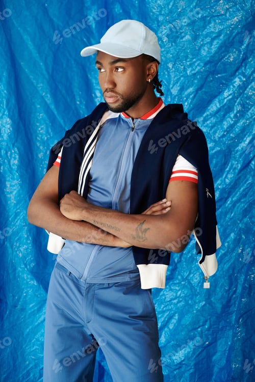 Preview: Handsome young man poses confidently against a vibrant blue backdrop
