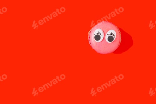 Preview: Tasty pink cookie with two eyes on a vibrant red background