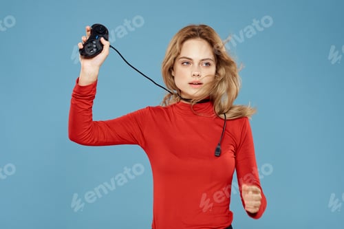 Preview: Pretty woman gamepad in hands playing games entertainment consoles to lifestyle blue background red