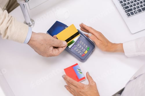 Preview: Overview of hands of senior buyer holding credit card over screen of terminal