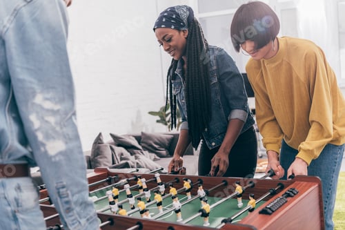 Preview: cropped shot of young multiethnic friends playing table soccer