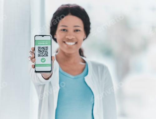 Preview: Shot of a young woman standing alone in the clinic and showing her Covid passport on her cellphone
