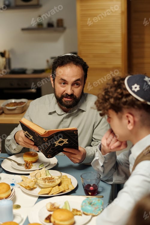 Preview: Focus on bearded mature man in kippah looking at his pre-teen son