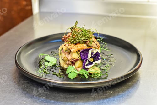 Preview: Close-up of a small black plate filled to the brim with a freshly cooked meal