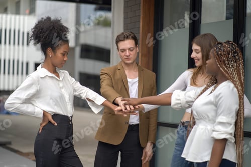 Preview: Multicultural colleagues showing unity with hands stacked together