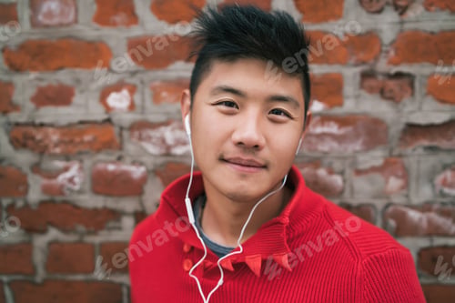Preview: Asian boy listening to music with earphones.