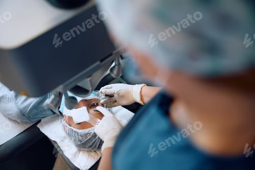 Preview: Close up of ophthalmologist preparing female patient for laser surgery at eye clinic.