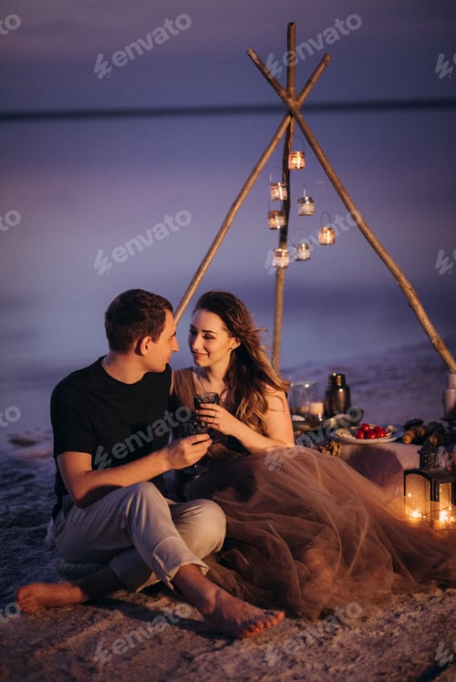 Preview: young couple having a picnic on the beach