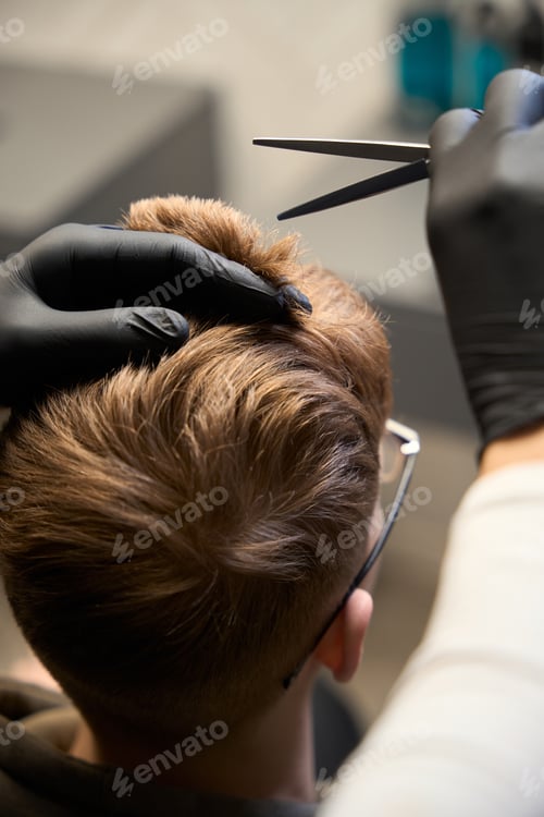 Preview: Cropped view of Caucasian hairstylist serving visitor in hairdressing salon