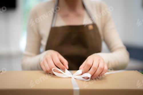 Preview: Woman hands wrapping a present in a box in the shop