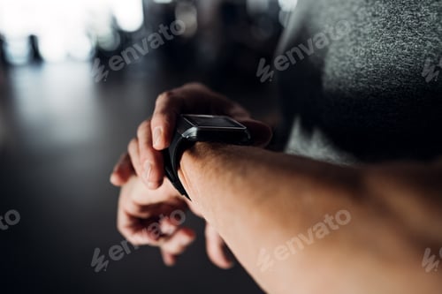 Preview: A midsection of man in gym measuring time while doing exercise. Copy space.