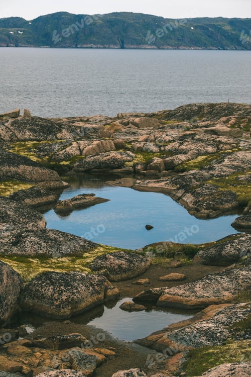 Preview: Serene Nordic Landscape with Coastal Rock Pools and Mountain View