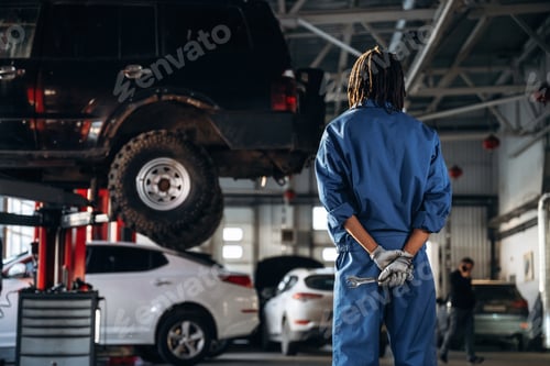 Preview: Tools in hands. Male mechanic is with car in garage