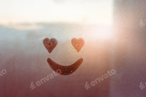Preview: Happy smile face heart-shaped eyes painted on window flooded with raindrops on glass in sunset city