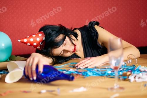 Preview: Young woman with sleeping at table in messy room after birthday party
