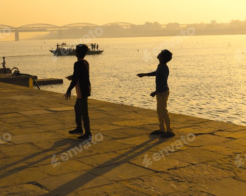 Preview: Children on a beach with kites, enjoying the evening sunset soaring their kites in the sky