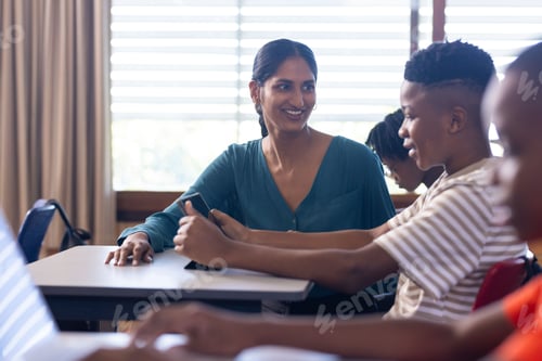 Preview: In school, Indian female teacher helping students using tablets in classroom, engaging in learning