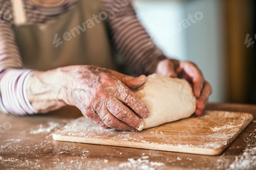 Preview: An unrecognizale senior woman kneading dough in the kitchen at home.
