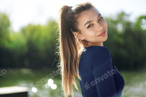 Preview: Portrait of a young smiling woman wearing sportswear in morning park