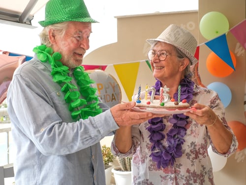 Preview: Joyful elderly couple celebrates a birthday in a festive and colorful setting.