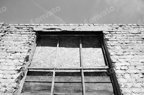 Preview: Low angle greyscale shot of an old concrete building with a broken window
