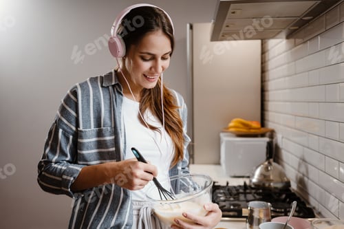 Preview: Pleased beautiful woman smiling and making pancakes dough