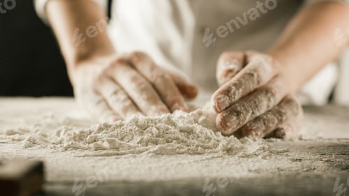 Preview: Male chef hands knead dough with flour on kitchen table