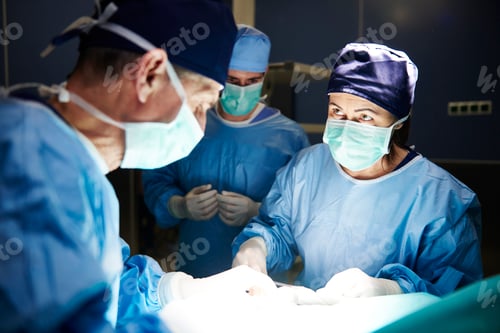 Preview: Team of surgeons working together during operation in darkness