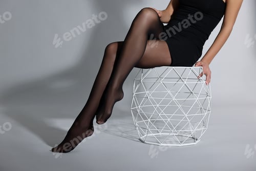 Preview: Woman with beautiful long legs wearing black tights on light background, closeup