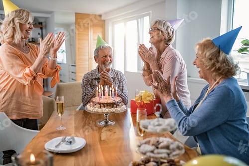 Preview: Group of cheerful seniors having fun while celebrating man's birthday at home.