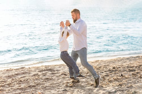 Preview: Father and son have fun on the summer beach. The father rolls and swings his hands
