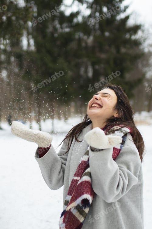 Preview: A beautiful girl smiles and enjoys the winter weather. Winter in the park. Snowy weather. Snowing.