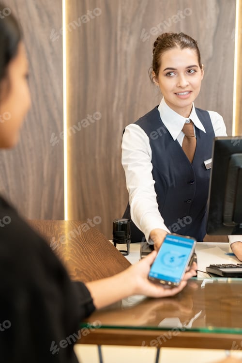 Preview: Young hotel receptionist looking at female client