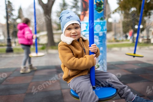 Preview: A boy on a playground in an autumn park rides on a swing in cloudy weather