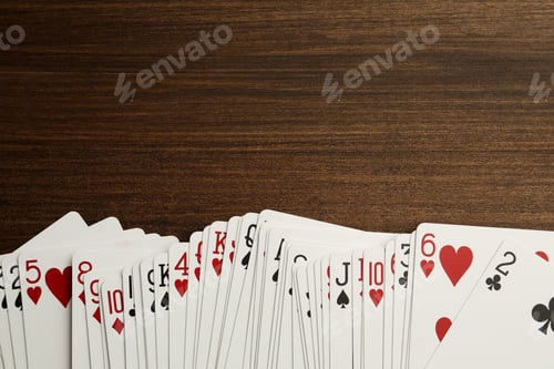 Preview: Deck of playing cards on wooden table, top view. Space for text
