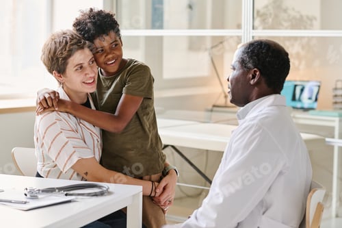 Preview: Mom with son smiling while talking to doctor about treatment during their visit at clinic