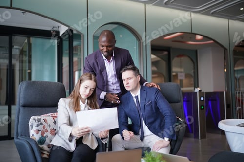 Preview: Image of young businessmen and colleague discussing document in laptop and touchpad at meeting