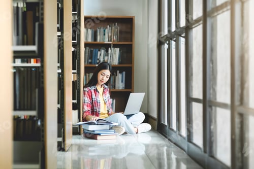 Preview: Young university student using laptop for online learning, searching and learning at library.