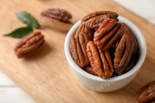 Preview: Shelled pecan nuts in bowl on wooden board. Space for text