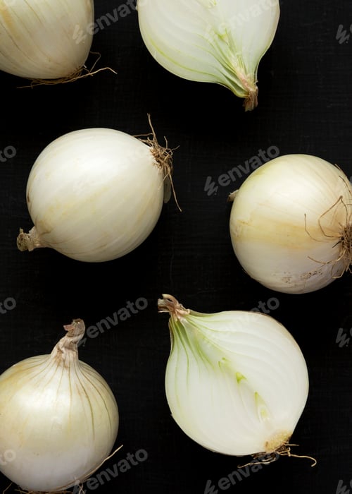 Preview: Raw white onions on a black surface, top view. Flat lay, overhead, from above. Closeup.