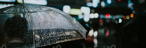 Preview: Man walking with a transparent umbrella in a city at night