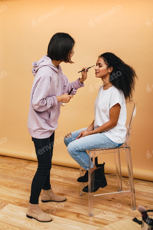 Preview: Female artist applying make up on fashion model before photo shoot