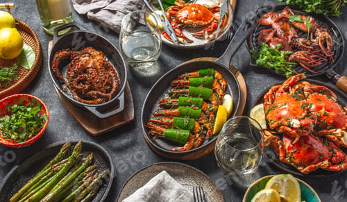 Preview: Set table with seafood dishes - cooked crabs, tiger shrimps, grilled octopus and squids on cast iron