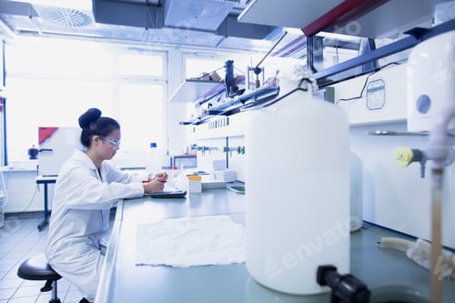 Preview: Young female scientist contemplating research notes on lab workbench