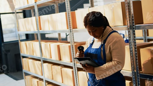 Preview: Young adult working with scanner and tablet in depot