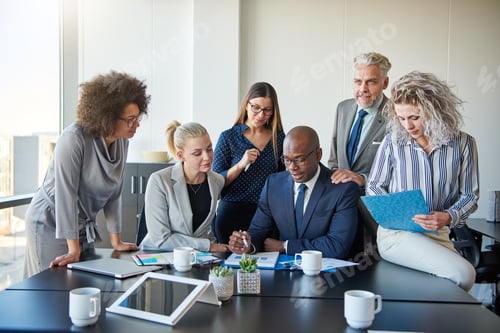 Preview: Diverse group of colleagues discussing paperwork together in an office