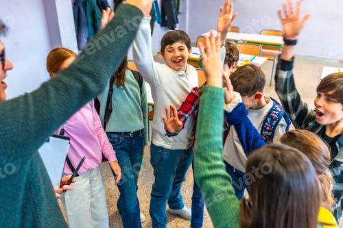 Preview: Happy students and teacher raising hands together in classroom