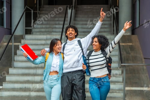 Preview: Students celebrating raising hands together outdoors the university