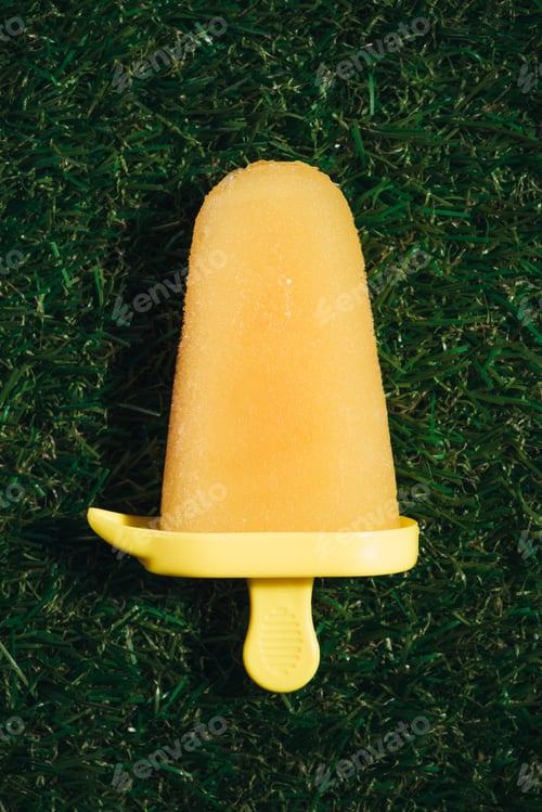 Preview: Sweet yellow fruit Popsicle on green grass background