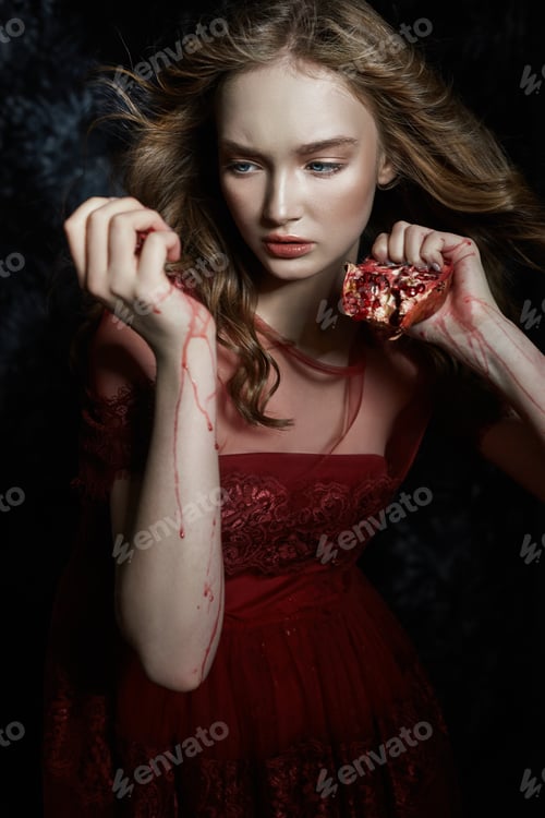 Preview: Beautiful blonde girl with pomegranate fruit in her hands. Spring portrait of girl in red dress